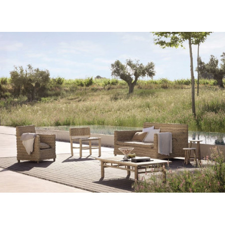 Conjunto de sillón y sofá de dos plazas para jardín fabricado en esparto, en un rincón del jardín