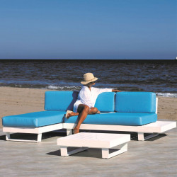 Conjunto de chaiselongue para exterior en color blanco y cojinería azul, con el mar de fondo.
